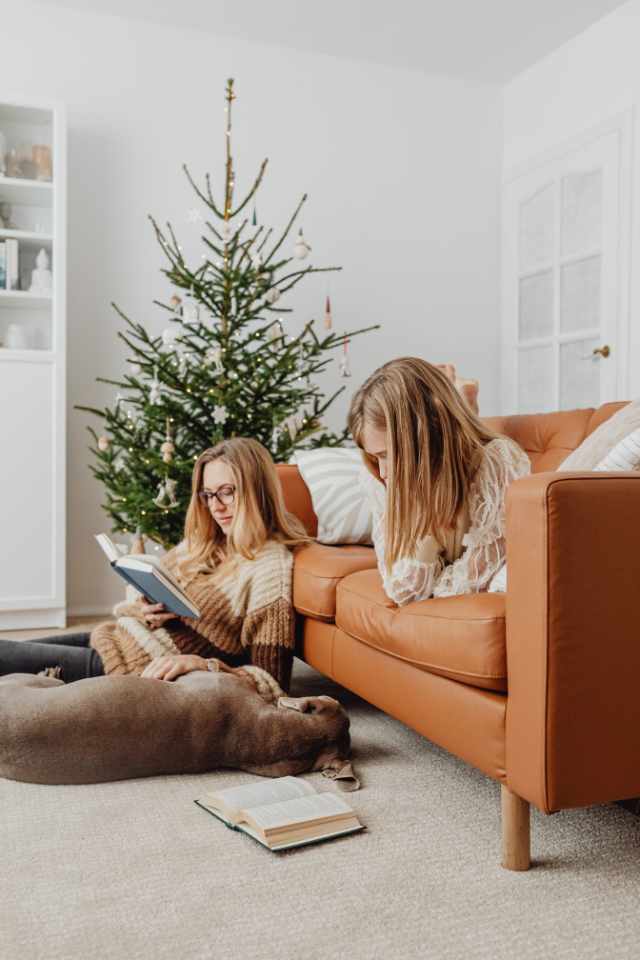 girls reading in living room with plush white carpet and leather couch